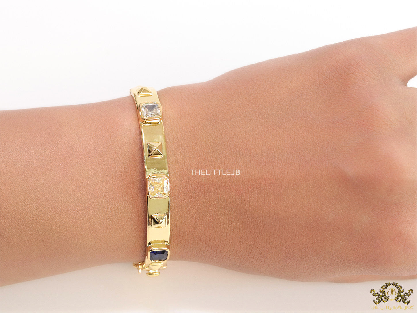 Band style bracelet in gold plating with gold plated details and multi colour stones