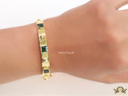 Band style bracelet in gold plating with gold plated details and emerald green colour stones