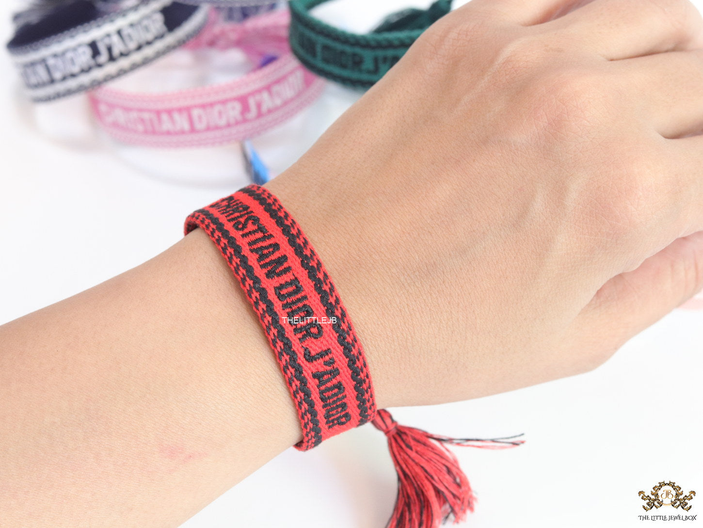 Adjustable red woven bracelet with black knitted alphabets and tassels