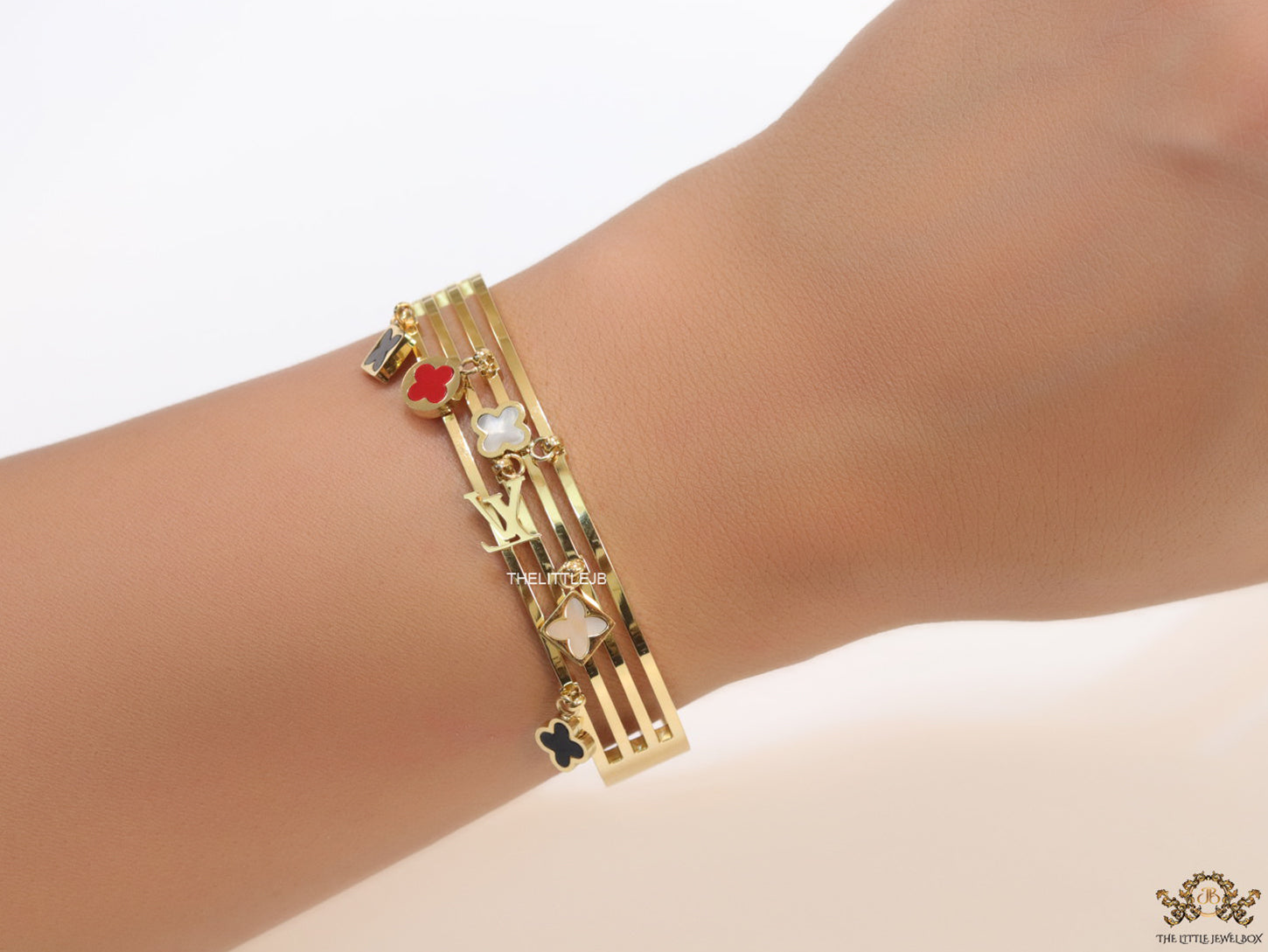 Multilayered golden bracelet with alphabets and coloured clover charms
