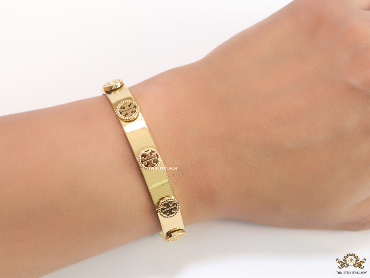 Gold plated open band bracelet with twin T motifs