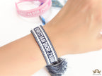 Adjustable dark grey woven bracelet with knitted alphabets and tassels