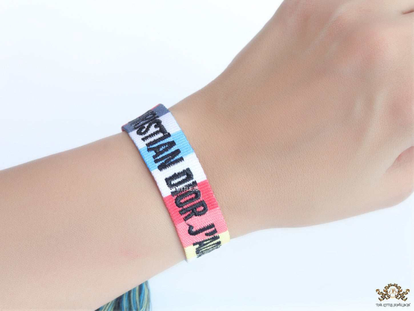 Adjustable multi color woven bracelet with black knitted alphabets and tassels