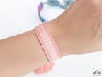 Adjustable pastel pink woven bracelet with knitted alphabets and tassels
