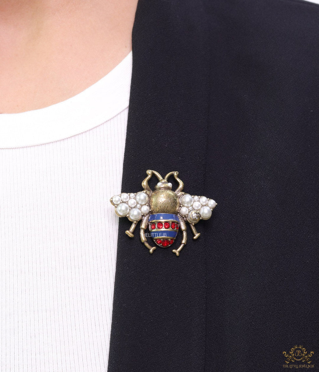 Antique gold finish double G bee brooch with blue details and white and red stones