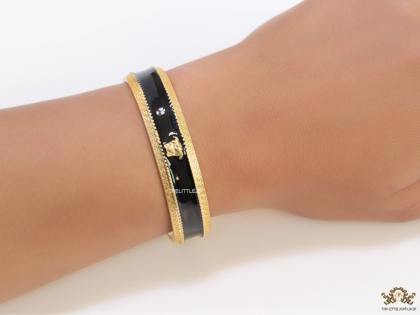 Band style black enamel bracelet with gold plated details and gold plated Medusa face motif