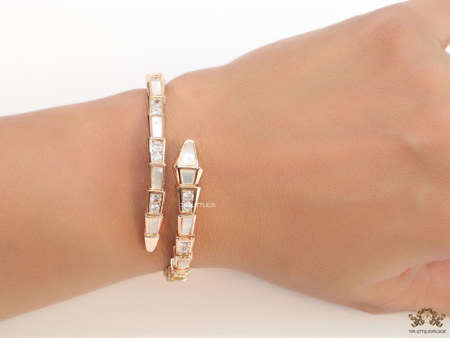 Open top rose gold plated minimal serpentine bracelet with cubic zirconia stones and pearl white stones.