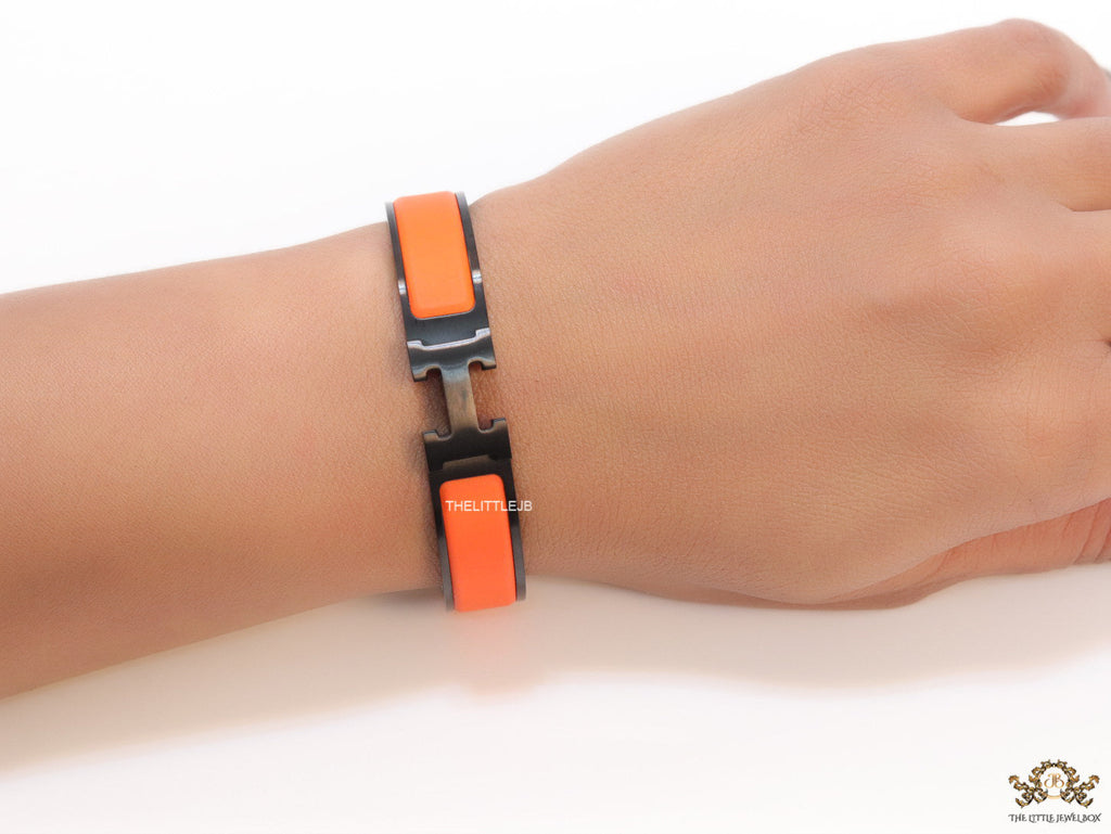 Premium collection band style bracelet in matt orange with black metallic details and black T alphabet motif