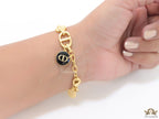 Gold plated link chain bracelet with charms, trinkets and black enamel charm with alphabets