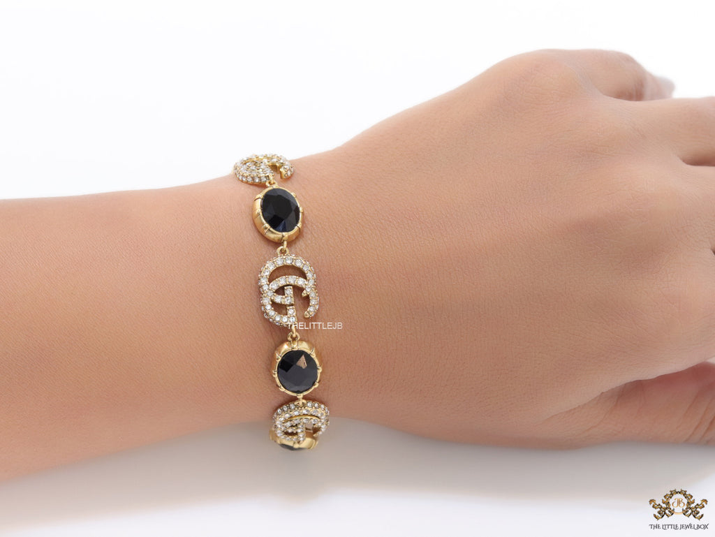 Gold plated linked chain bracelet with black stones and twin G alphabet motif