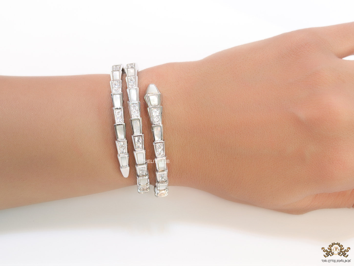Triple line platinum plated minimal serpentine bracelet with cubic zirconia stones and pearl white stones.