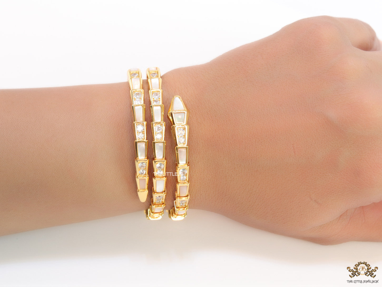 Triple line gold plated minimal serpentine bracelet with cubic zirconia stones and pearl white stones.
