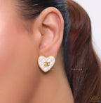 White textured heart shaped studs with twin C motif in golden finish