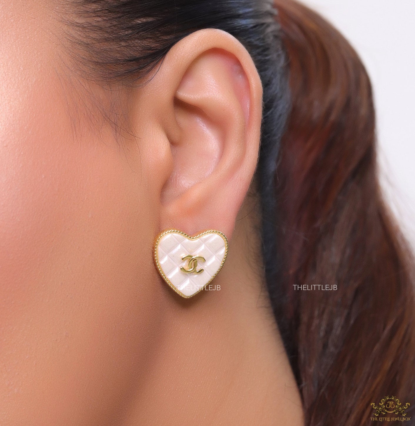 White textured heart shaped studs with twin C motif in golden finish