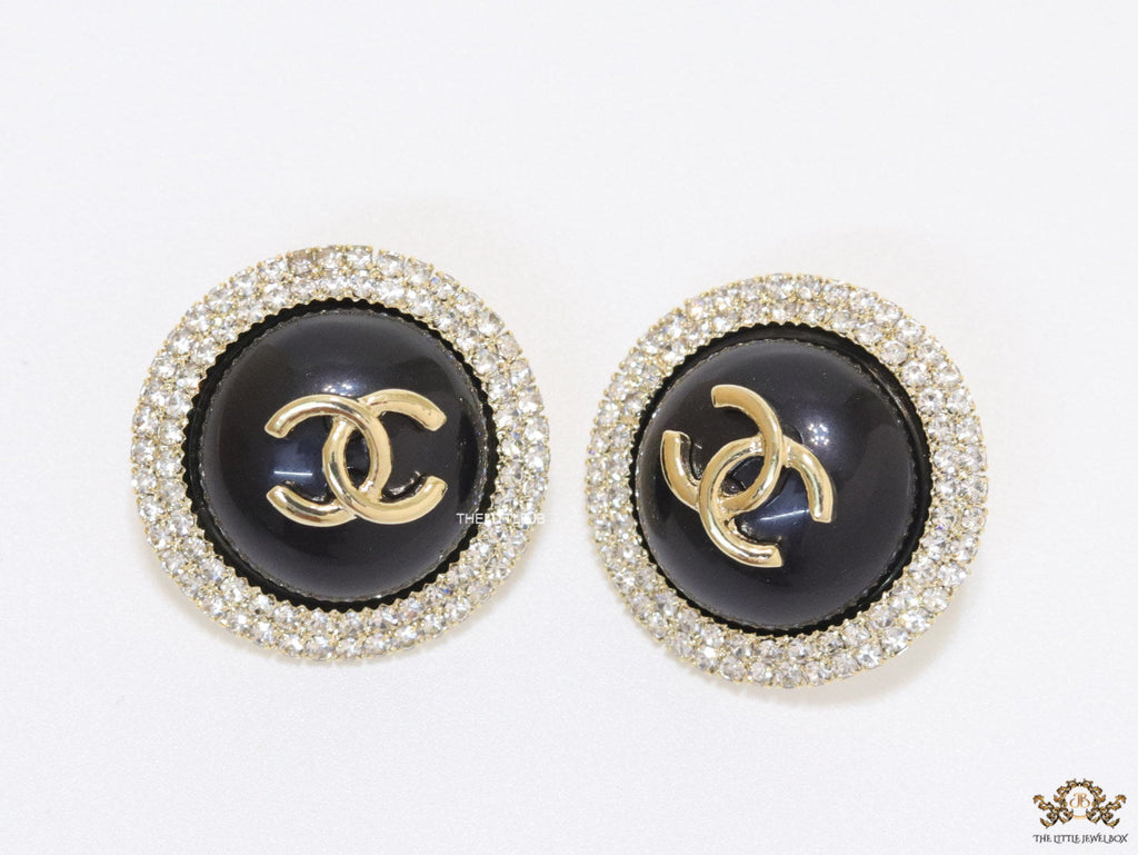 Round black stud earrings with golden twin C motifs lined with cz