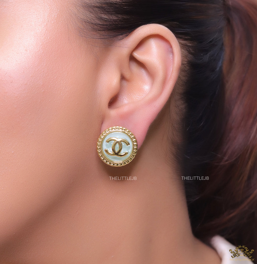 Twin C motif gold plated round studs on mint green acrylic base