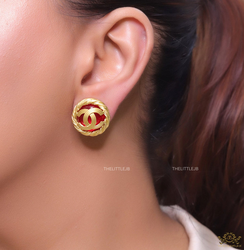 Twin C motif matt gold plated round studs on red base