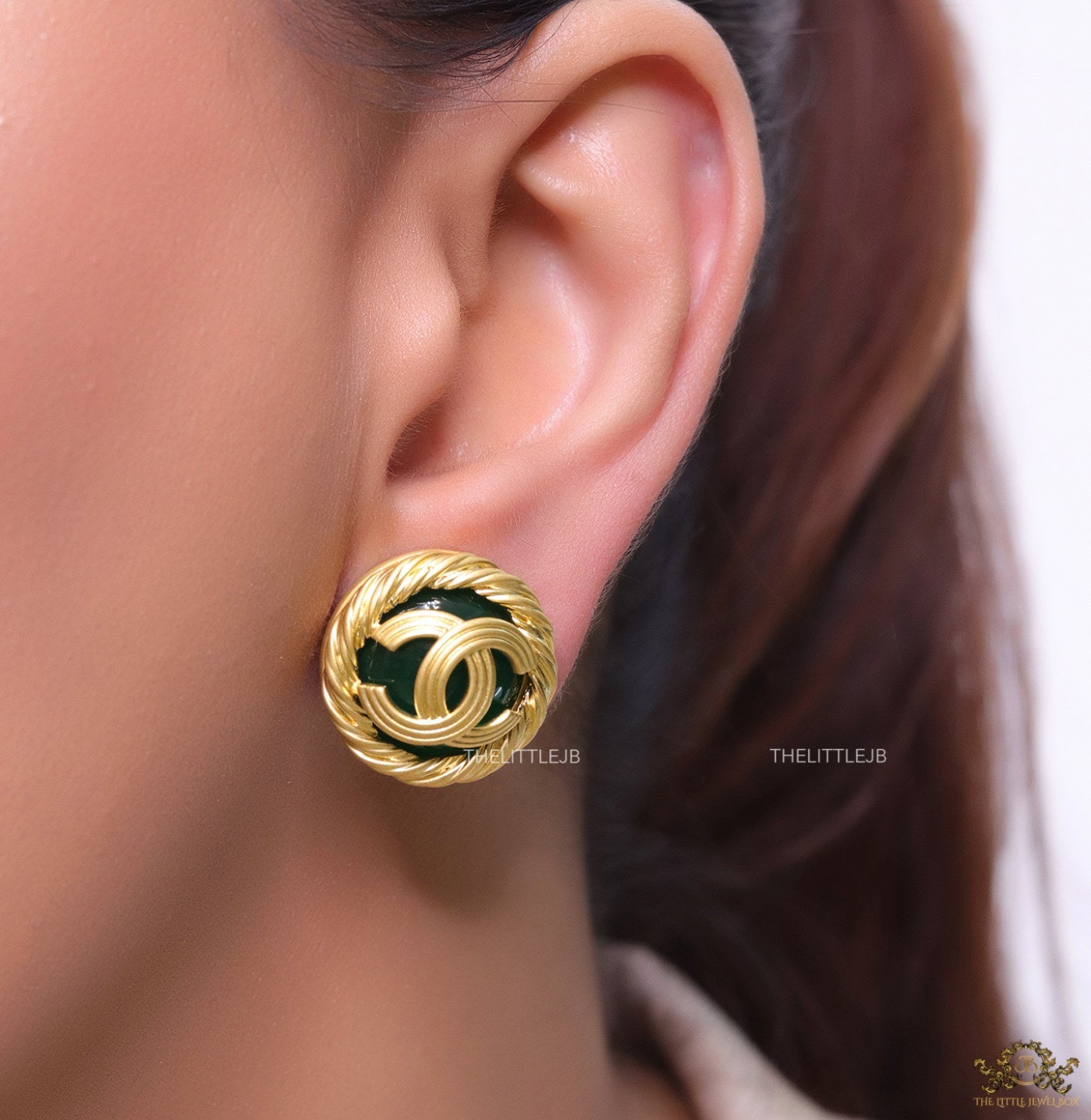 Twin C motif matt gold plated round studs on deep green base