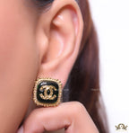 Square black and golden stud earrings with golden twin C motifs