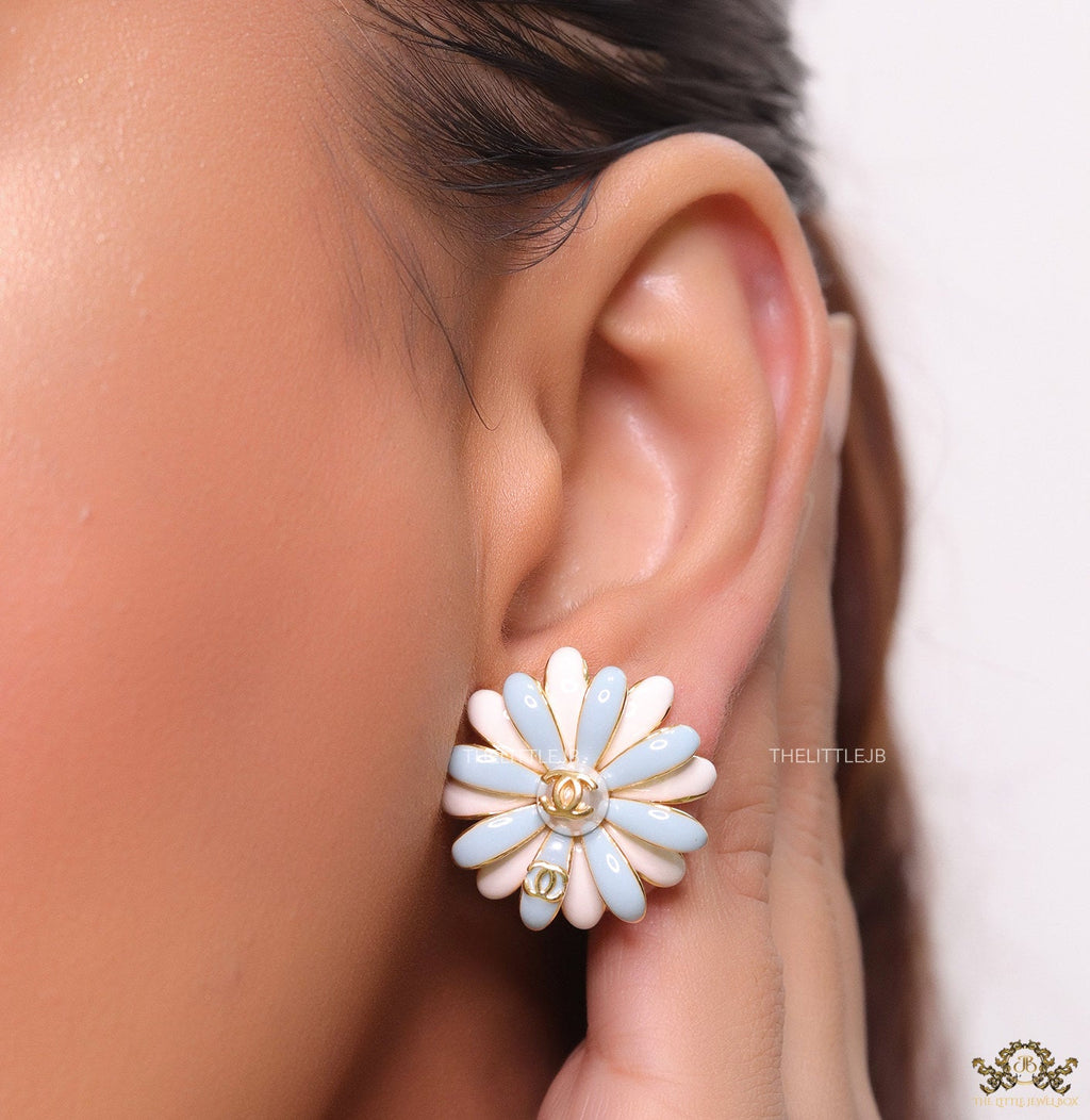 Off-white and soft blue daisy studs with golden details twin alphabet double C motif.