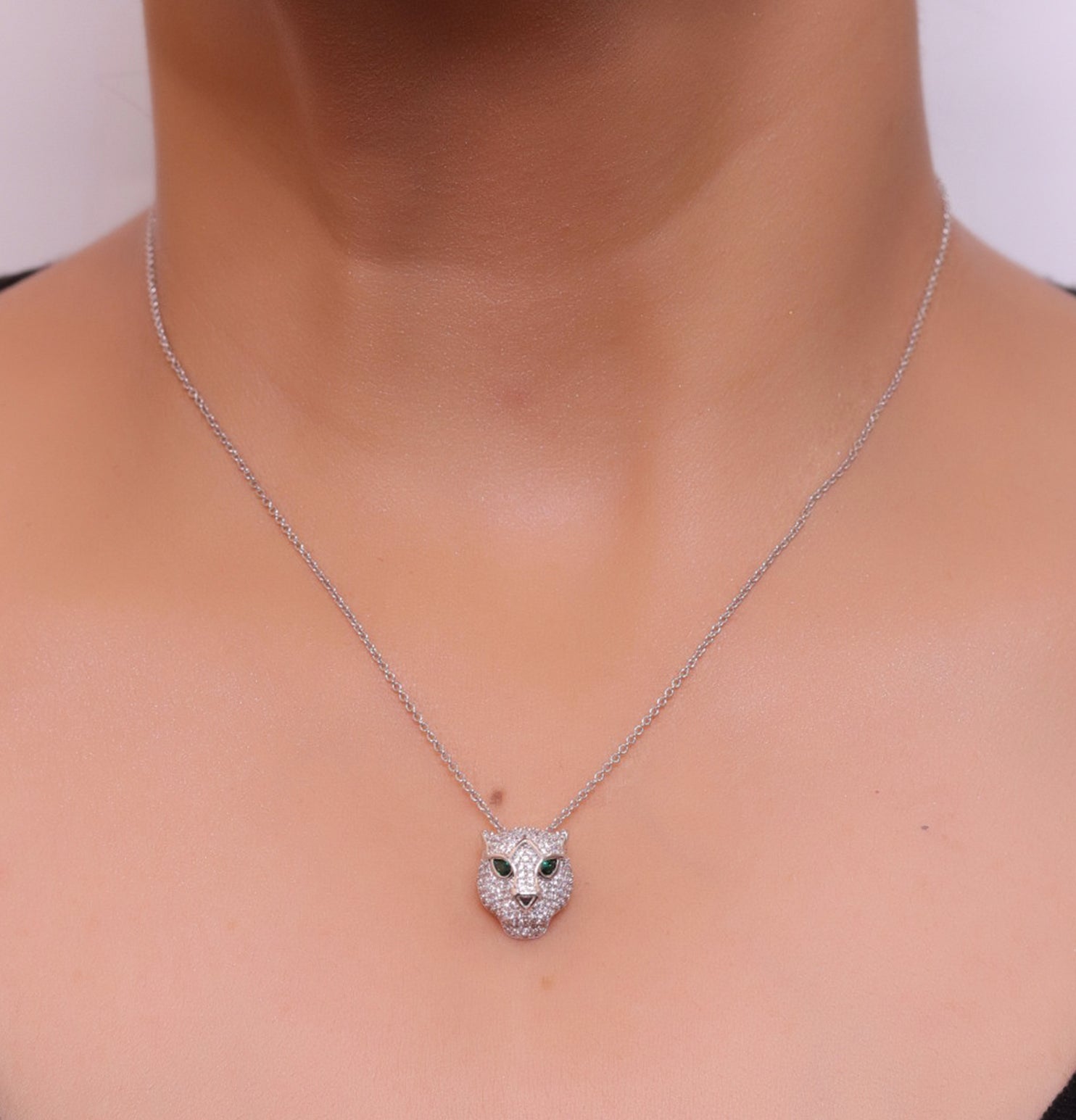 Platinum plated cubic zirconia stones panther face motif pendant with emerald green stones details on sleek Platinum plated chain