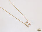 Gold chain necklace with white enamel H motif